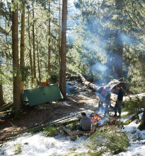 Kampplek met vuur en tenten waar deelnemers bezig zijn tijdens hike in Vogezen