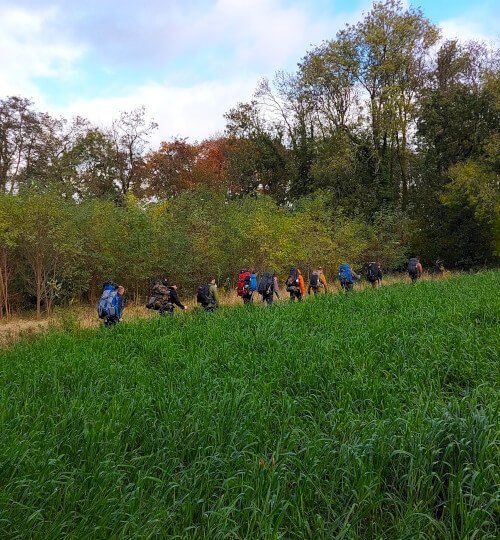 Deelnemers wandelen met rugzakken door Limburgs landschap tijdens MTA 2-daagse Pieterpad