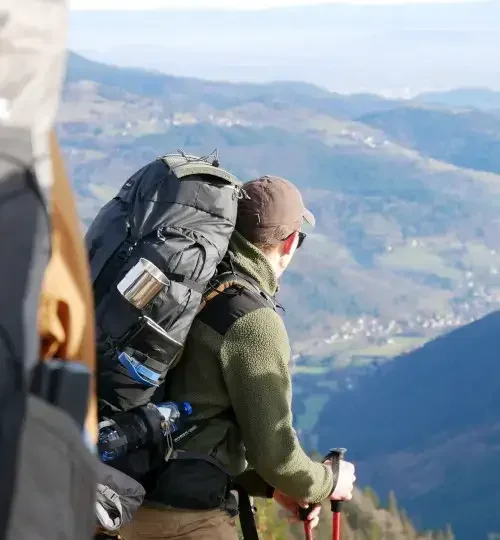 Deelnemer kijkt uit over Franse Vogezen tijdens hike over bergkam tijdens MTA 3-daagse