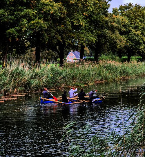Teamtraining deelnemers varen met zelfgebouwd vlot op water in Nederland